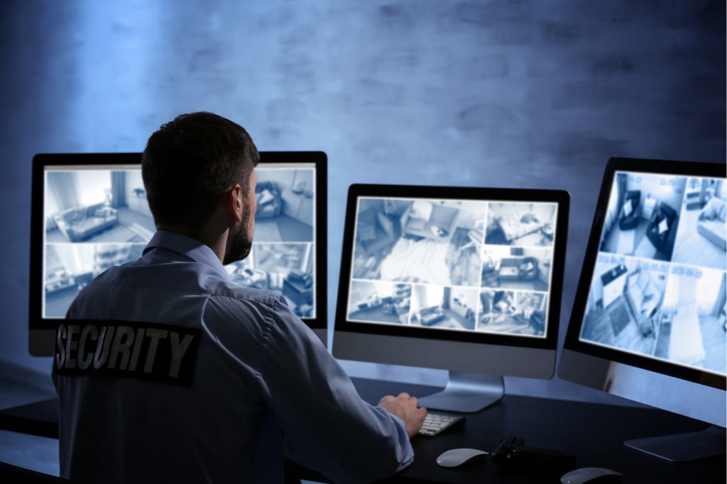 Security operator monitoring camera feeds on multiple screens