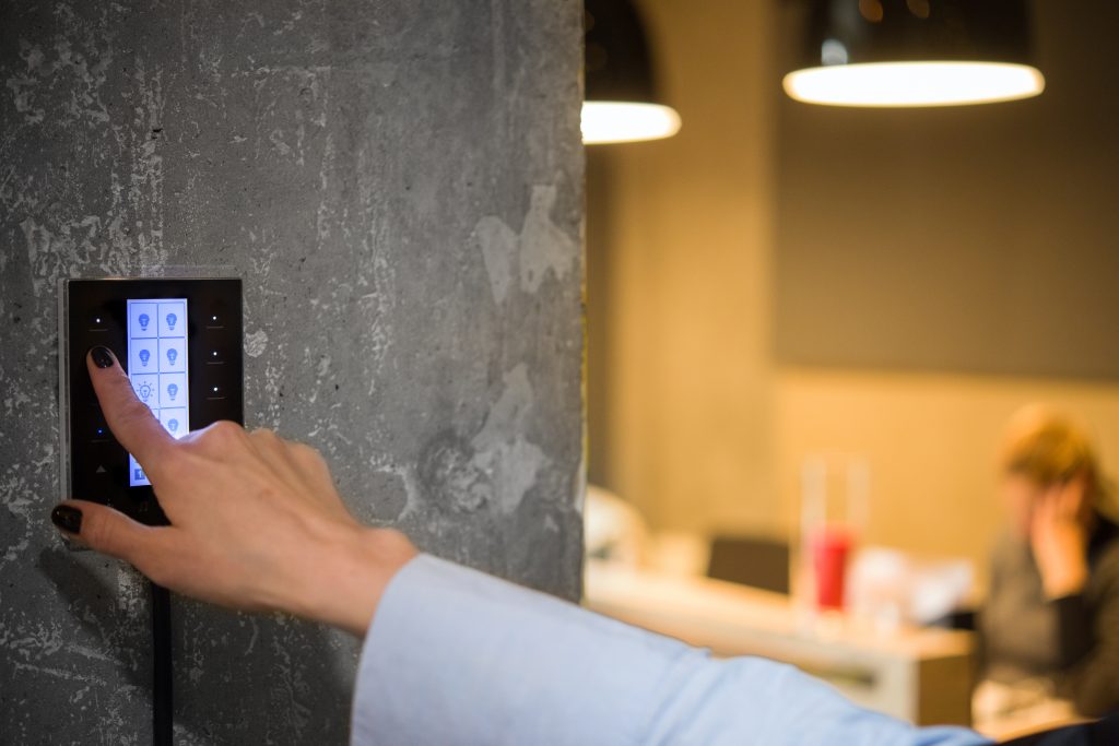 Hand pressing a wall-mounted smart home keypad